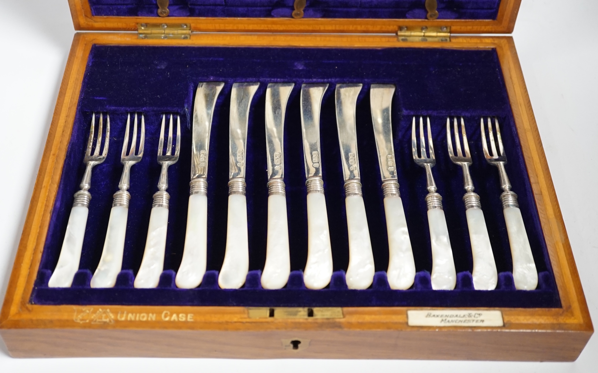 A cased set of twelve pairs of Edwardian silver and mother of pearl pistol handled dessert eaters, Josiah Williams & Co, London, 1908, knife 17.6cm.